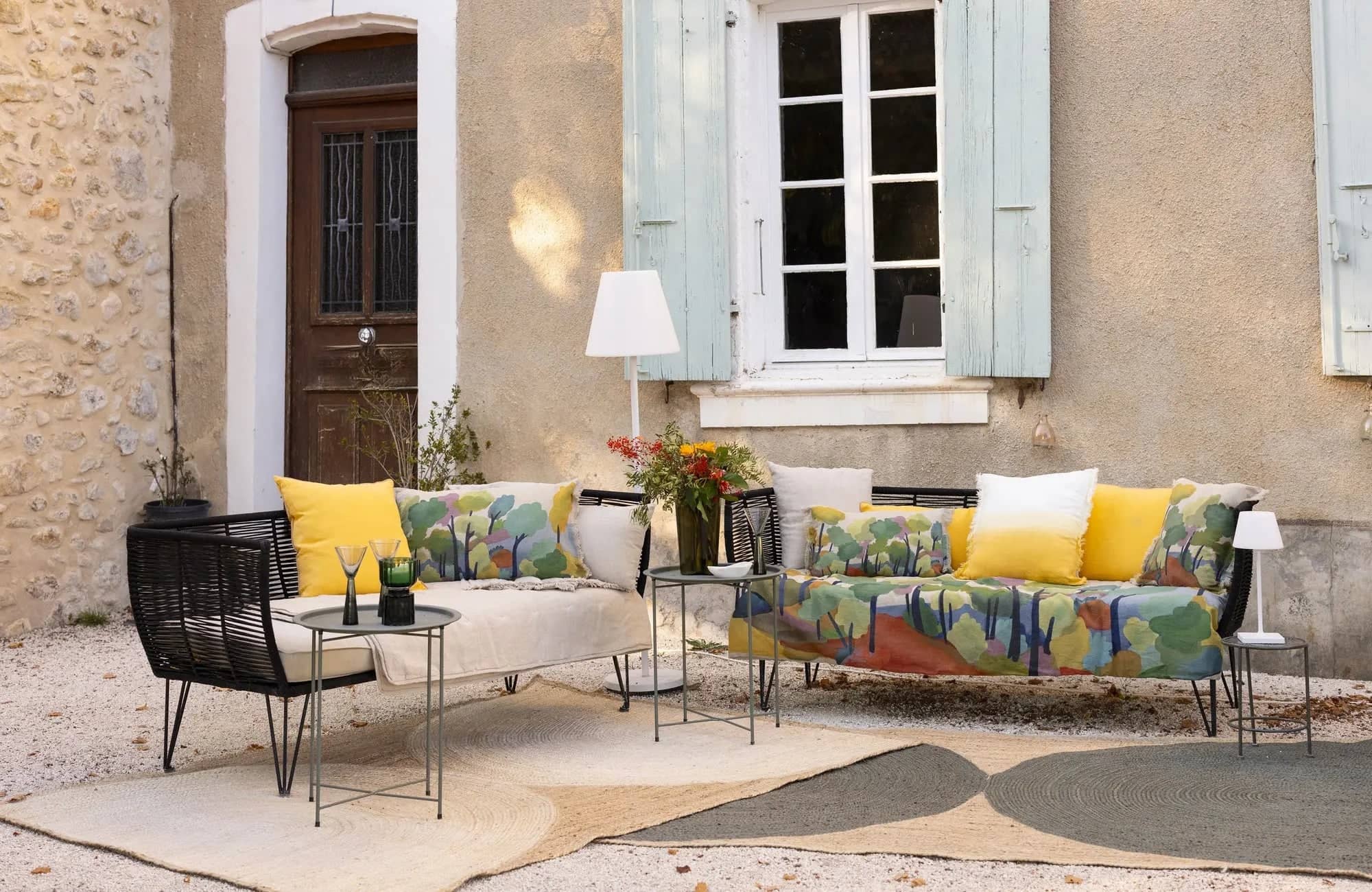 Coin salon extérieur avec canapé et fauteuil colorés, décoré avec coussins et linge de maison extérieur